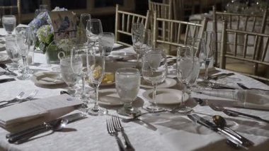 Zarif cam takımları, güzel çatal bıçakları ve büyüleyici çiçek dekoru olan güzel bir yemek masası.