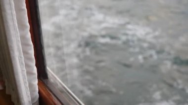 Hoş bir pencere ve yumuşak perdeler tarafından çerçevelenmiş bir tekneden görülen suyu tasvir eden güzel, sakin bir sahne.