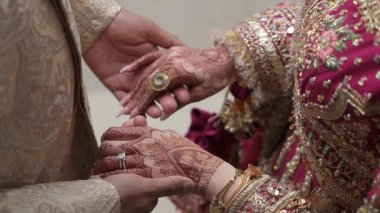 Büyüleyici ve güzel bir an. Gelinliğin el değiştirmesi sergileniyor. Karmaşık kınalarla süslenmiş.