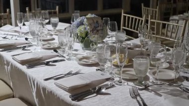 Zarif cam takımları, güzel çatal bıçakları ve büyüleyici çiçek dekoru olan güzel bir yemek masası.
