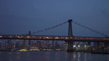 Williamsburg Köprüsü 'nün çarpıcı gece manzarası New York gökyüzü manzarasına karşı güzelce aydınlatılmış.