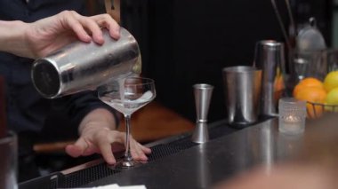 Yetenekli bir barmen bardağa ustalıkla kokteyl döker. Etkileyici miksoloji yetenekleri sergiler.