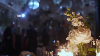 Beyaz güller ve mumlarla süslenmiş güzel bir masa, canlı bir akşam kutlaması..