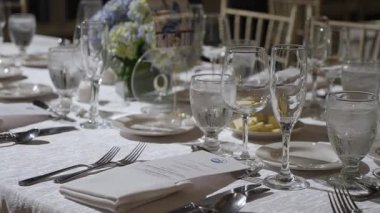 Zarif cam takımları, güzel çatal bıçakları ve büyüleyici çiçek dekoru olan güzel bir yemek masası.