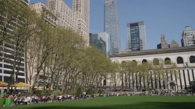 Çağdaş şehir manzaralarının ortasında güneşli bir günün keyfini çıkaran çeşitli insanların olduğu canlı ve canlı bir şehir parkı sahnesi.