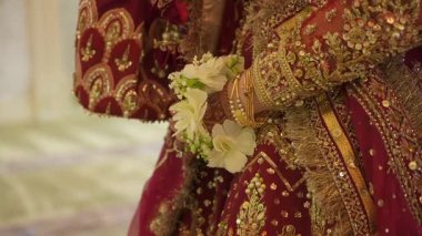 Şatafatlı kıyafetlerle süslenmiş nefes kesici bir gelin, güzel, karmaşık gelenekler ve canlı çiçeklerle süslenmiş bir gelin.