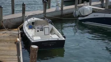NEW YORK, ABD - 20 Mayıs 2025: Sakin sular ve kırsal ahşap rıhtımlarla çevrili huzurlu bir marinaya küçük bir tekne güvenli bir şekilde yanaştı