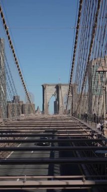 NEW YORK, ABD - 22 Nisan 2025: İnsanlar Brooklyn Köprüsü 'nde arkalarında çarpıcı ve berrak bir ufuk çizgisi olan sakin bir gezintinin tadını çıkarıyorlar