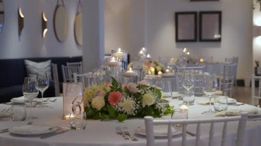 Yüzen mumlar, canlı çiçekler ve sofistike cam eşyalar sergilenen şaşırtıcı derecede düzenlenmiş bir yemek masası.