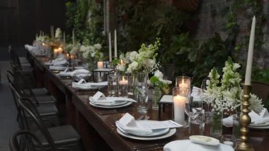 Güzel bir yemek masası, mumlar ve çiçeklerle büyüleyici bir bahçede, toplanmak için mükemmel.