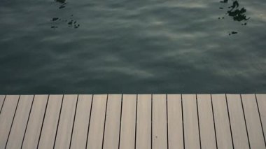 Sakin ve huzurlu doğal bir sahne, sakin, hafif dalgalı bir su, temiz ve davetkar bir ahşap rıhtımın yanında.