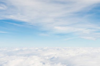 Mavi gökyüzü manzarası ve kabarık bulutlar, bir uçağın penceresinden çekilmiş bir resim..