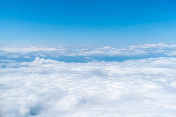 stock image A view of the blue sky and fluffy clouds, a picture taken from the window of an airplane.