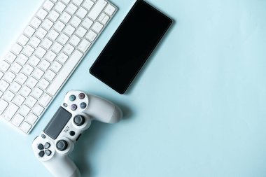 Oyun arka planında joystick ve gamepad, oyun konsolu, kulaklıklarda mavi arka plan, çevrimiçi öğrenme konsepti. Metin için kopyalama alanı olan en üstteki görünüm