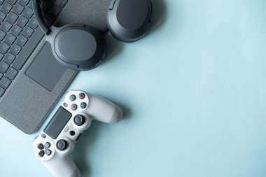Oyun arka planında joystick ve gamepad, oyun konsolu, kulaklıklarda mavi arka plan, çevrimiçi öğrenme konsepti. Metin için kopyalama alanı olan en üstteki görünüm