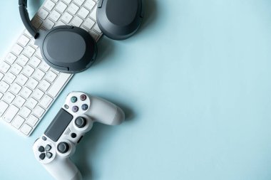 Oyun arka planında joystick ve gamepad, oyun konsolu, kulaklıklarda mavi arka plan, çevrimiçi öğrenme konsepti. Metin için kopyalama alanı olan en üstteki görünüm