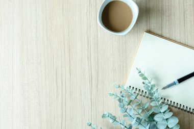 Boş kağıt, defter, kahve fincanı, kalem, beyaz masa üzerinde metin veya tasarım için kopyalama alanı olan bitki.