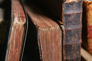Kütüphanedeki raflarda duran çok eski kitaplar. Bilginin sembolü olarak kitaplar.