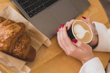 Bir fincan kağıt kahve tutan kadın eli resimleri. Kahve konsept olsun. Dizüstü bilgisayarın en üst görüntüsü. Serbest çalışma..