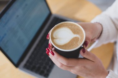 Bir fincan kağıt kahve tutan kadın eli resimleri. Kahve konsept olsun. Dizüstü bilgisayarın en üst görüntüsü. Serbest çalışma..