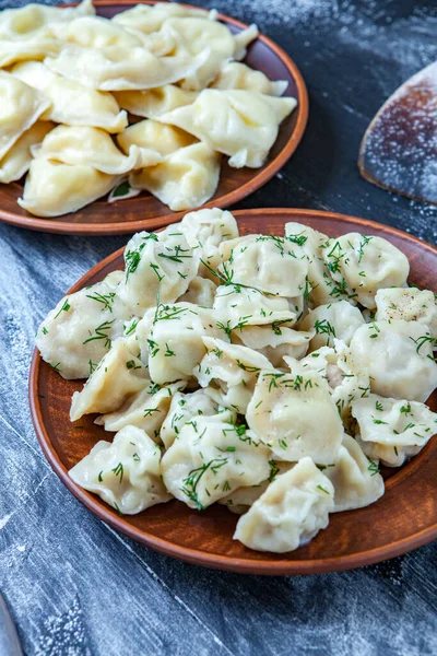 Traditional russian pelmeni or ravioli, dumplings with meat on wood black background. Russian food and russian kitchen concept.