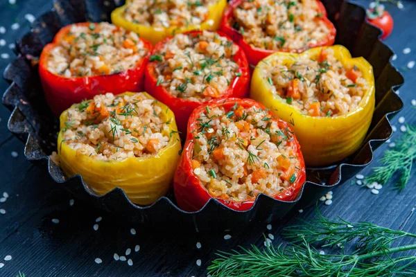 Stuffed pepper. Stewed pepper with rice and minced meat. Baked peppers in a cast iron pan on a black background. Healthy Romanian food.