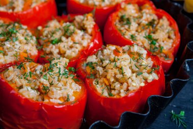 Doldurulmuş biber. Biberli pilav ve kıyma. Siyah arka planda, dökme demir bir tavada pişmiş biber. Sağlıklı Romanya yemekleri.