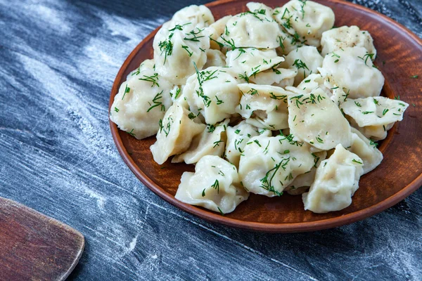 Traditional russian pelmeni or ravioli, dumplings with meat on wood black background. Russian food and russian kitchen concept.