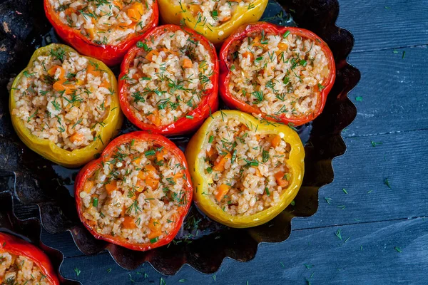 Stuffed pepper. Stewed pepper with rice and minced meat. Baked peppers in a cast iron pan on a black background. Healthy Romanian food.