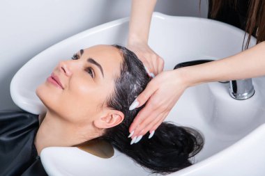 professional hairdresser washing hair of young woman in beauty salon. close up of woman's hair in beauty salon, hairstyle concept