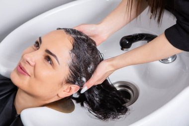 professional hairdresser washing hair of young woman in beauty salon. close up of woman's hair in beauty salon, hairstyle concept