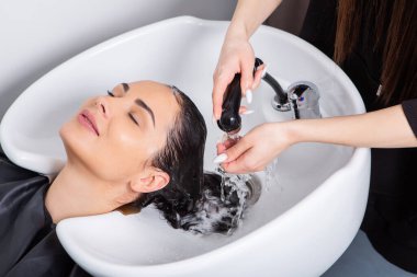 professional hairdresser washing hair of young woman in beauty salon. close up of woman's hair in beauty salon, hairstyle concept