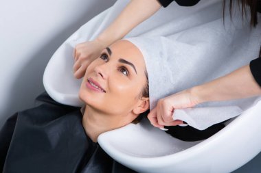 professional hairdresser washing hair of young woman in beauty salon. close up of woman's hair in beauty salon, hairstyle concept