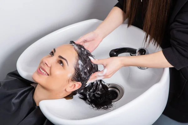 professional hairdresser washing hair of young woman in beauty salon. close up of woman\'s hair in beauty salon, hairstyle concept