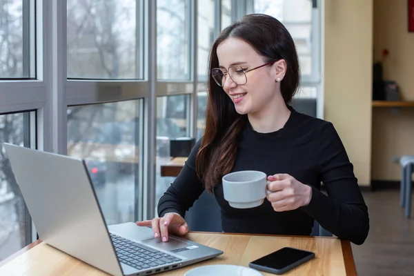 Beautiful businesswoman working on laptop in coffee shop. Female freelancer connecting to internet via computer. Blogger or journalist writing new article.