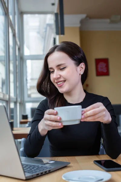 Beautiful businesswoman working on laptop in coffee shop. Female freelancer connecting to internet via computer. Blogger or journalist writing new article.