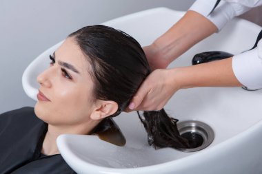 professional hairdresser washing hair of young woman in beauty salon. close up of woman's hair in beauty salon, hairstyle concept