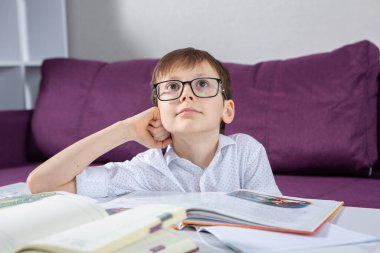 Young boy reading book at home. Education, childhood, homework and school concept.