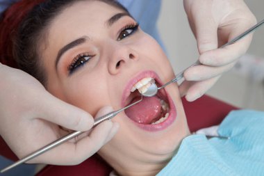 Dentist with assistant and patient at dental clinic. Dentistry. Close-up of a female patient having her teeth examined by dentist