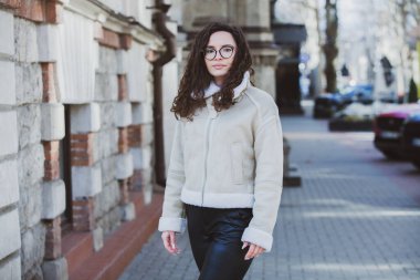 Esmer, kıvırcık saçlı, gözlüklü güzel bir kadın. Şehirde güneşin tadını çıkarıyor..