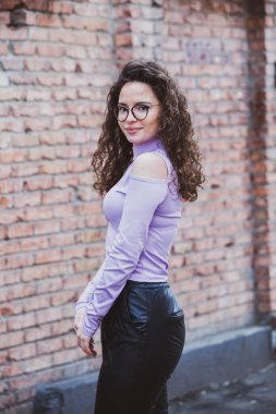 Esmer, kıvırcık saçlı, gözlüklü güzel bir kadın. Şehirde güneşin tadını çıkarıyor..