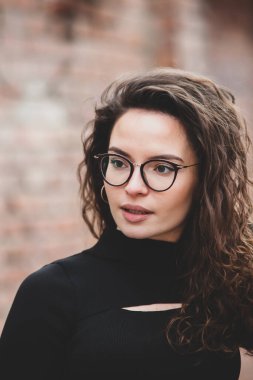 Esmer, kıvırcık saçlı, gözlüklü güzel bir kadın. Şehirde güneşin tadını çıkarıyor..