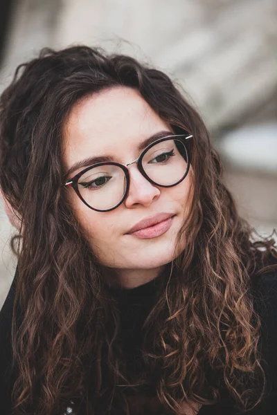 stock image Beautiful young woman with brunette curly hair, portrait in eye glasses enjoying the sun in the city.