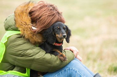 Kadın çimlerin üzerinde sevimli köpeğine sarılıyor..