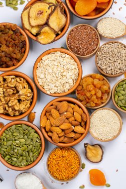 Sağlıklı vejetaryen gıda konsepti. Beyaz arka planda kurutulmuş meyve, fındık ve tohum çeşitleri. Üst görünüm.