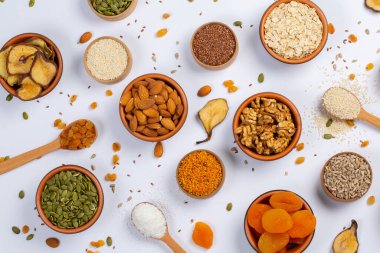 Sağlıklı vejetaryen gıda konsepti. Beyaz arka planda kurutulmuş meyve, fındık ve tohum çeşitleri. Üst görünüm.