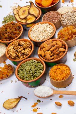 Sağlıklı vejetaryen gıda konsepti. Beyaz arka planda kurutulmuş meyve, fındık ve tohum çeşitleri. Üst görünüm.