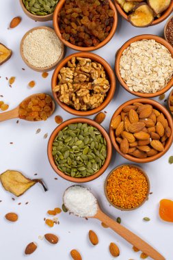 Sağlıklı vejetaryen gıda konsepti. Beyaz arka planda kurutulmuş meyve, fındık ve tohum çeşitleri. Üst görünüm.