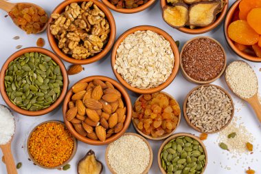 Sağlıklı vejetaryen gıda konsepti. Beyaz arka planda kurutulmuş meyve, fındık ve tohum çeşitleri. Üst görünüm.