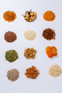 Sağlıklı vejetaryen gıda konsepti. Beyaz arka planda kurutulmuş meyve, fındık ve tohum çeşitleri. Üst görünüm.